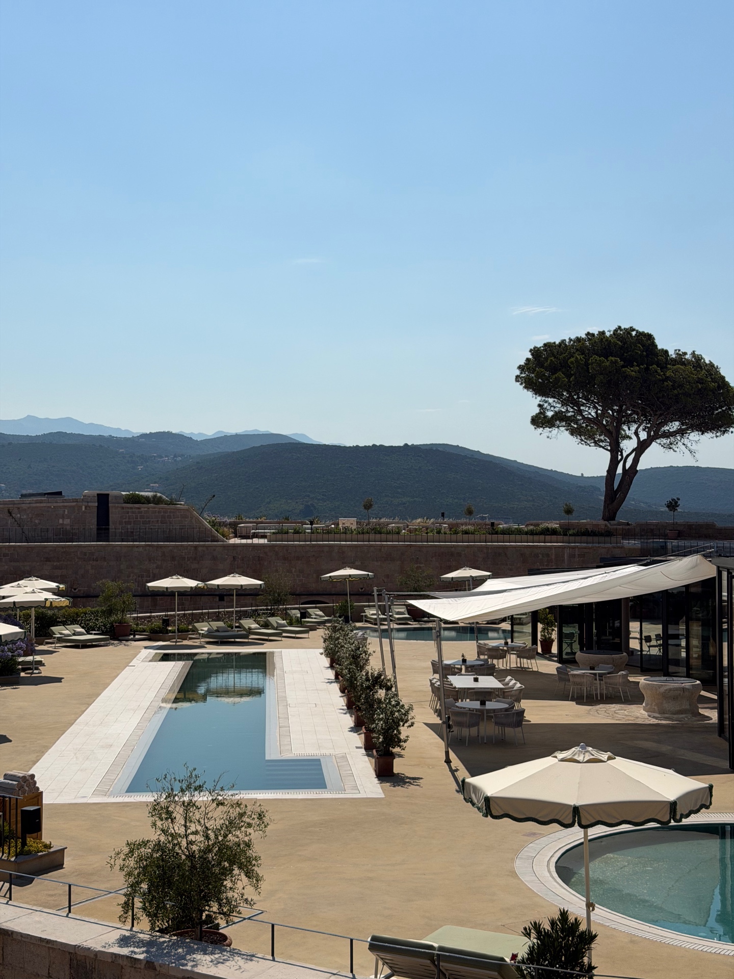 Sunlit terrace with pools, loungers and umbrellas at Mamula Island by Banyan Tree, Montenegro.