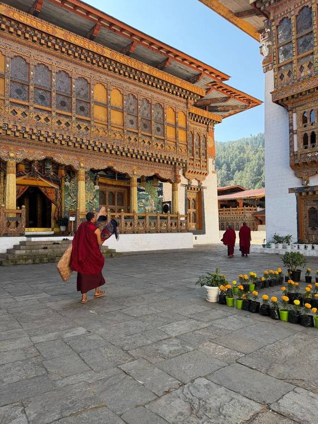 Buddhist monk crossing the courtyard of Punakha Dzong past its painted timber facade, Bhutan.