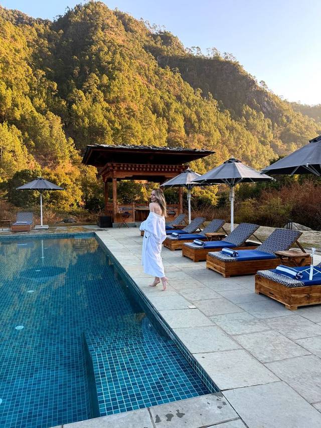 Luxury lodge pool terrace in Punakha, Bhutan, with timber pavilion and autumn Himalayan slopes.