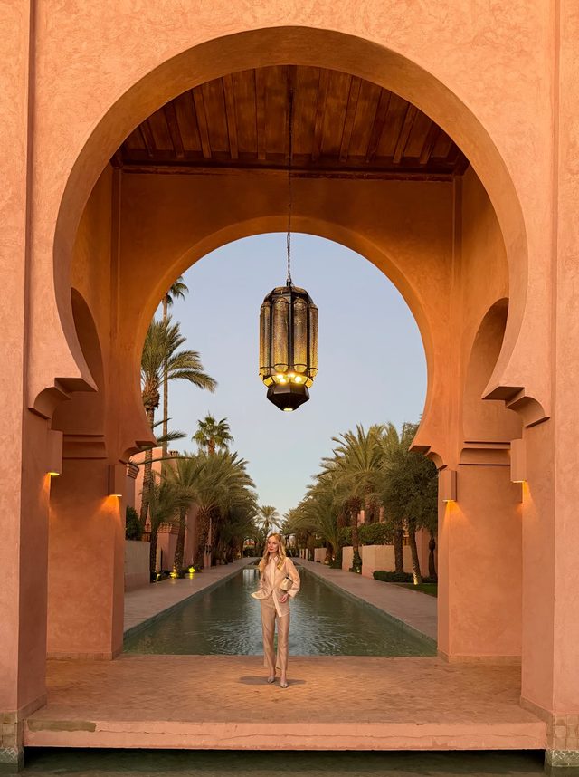 Luxury travel advisor Eva Szoradi beneath a Moorish arch and reflecting pool at Amanjena, Marrakech.