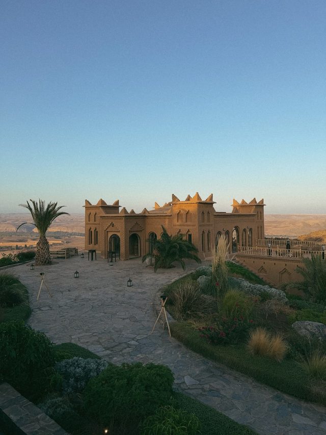 Kasbah-style luxury hotel at sunset overlooking the Agafay Desert near Marrakech, Morocco.