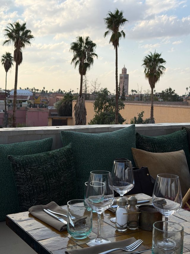 Rooftop restaurant table at sunset with views of the Koutoubia Mosque minaret, Marrakech medina.
